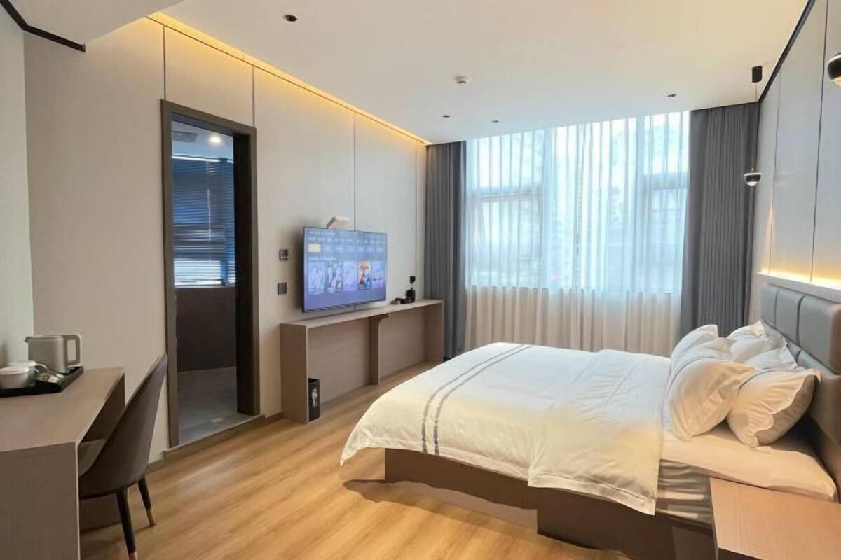 Una habitación de hotel moderna con una cama grande, un escritorio y una televisión.