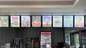 A food service area with digital menu boards displaying various dishes.