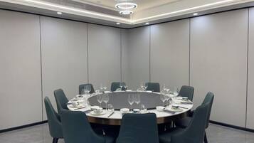 A conference room with a round table, chairs, and a ceiling light fixture.