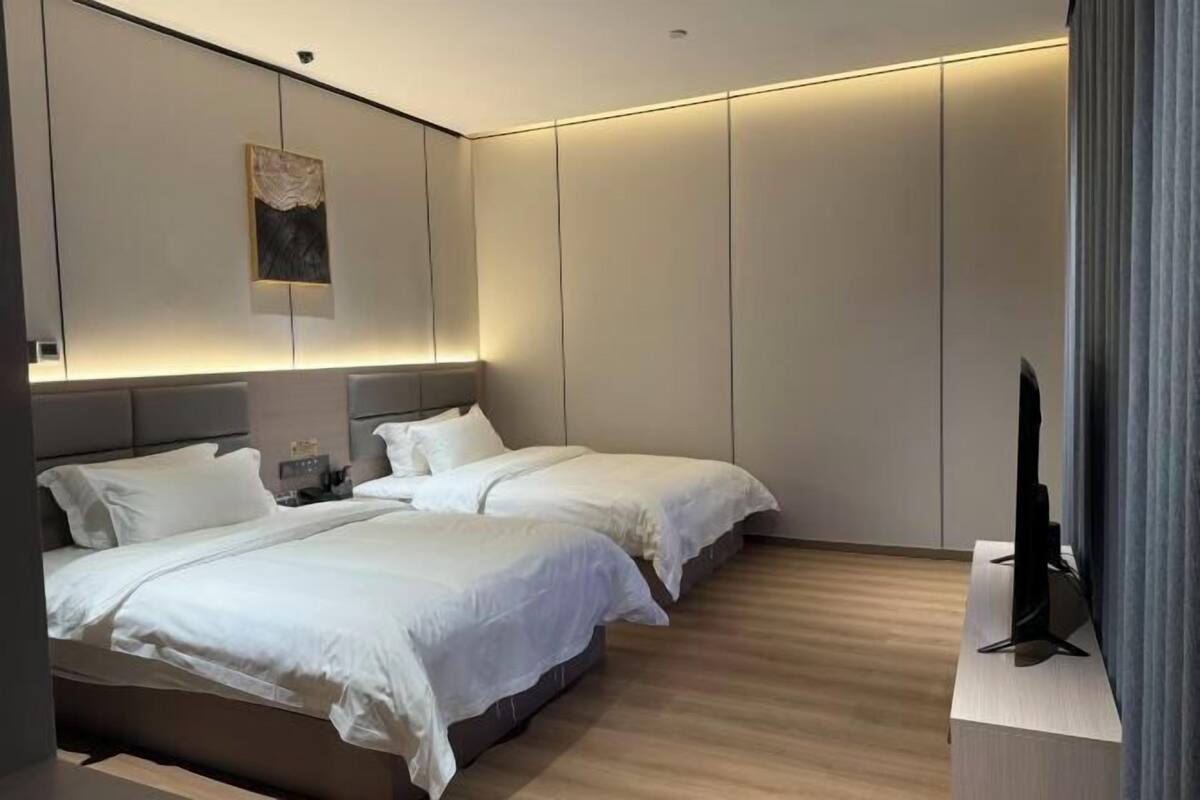 Una habitación de hotel moderna con dos camas, un televisor de pantalla plana y un diseño minimalista.