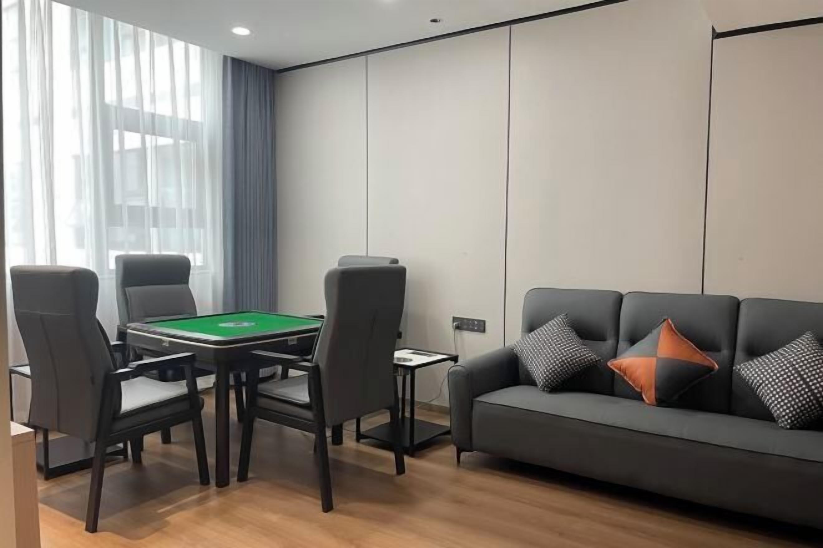 Uma sala de estar moderna com mesa de bilhar, um sofá com almofadas estampadas e uma grande janela com cortinas leves.