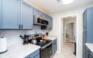 Modern kitchen with stainless steel appliances, light-colored tile floor, and ample countertop space.
