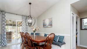 A dining area with a wooden table and chairs, a chandelier, a bench with cushions, and a painting on the wall. - AMAZING for Large Groups or Crews- 7 beds/ 4 bedrooms (Warner Robins)
