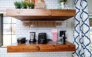 Kitchen area with a wooden countertop, shelf, and essential appliances.