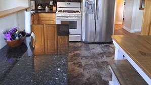 A modern kitchen with wooden cabinets, a stainless steel refrigerator, a gas stove, and a microwave. - Cowley Cozy Cottage 3 Bed/ 2 Bath (Cowley)