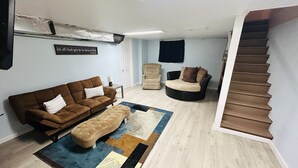 A living room with a brown sofa, a beige armchair, and a black sofa with cushions. There is a patterned rug on the floor. - Cowley Cozy Cottage 3 Bed/ 2 Bath (Cowley)