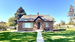 A single-story house with a brick facade, a front porch, and a clear pathway leading to the entrance. - Cowley Cozy Cottage 3 Bed/ 2 Bath (Cowley)