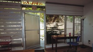Une pièce comprenant un banc en bois, un bureau et une chaise. Il y a une porte avec une pancarte au-dessus.
