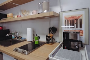 Cozinha com fogão, cafeteira e um cardápio emoldurado na parede.