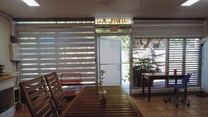 Une pièce avec une table en bois, des chaises, une petite plante et une fenêtre avec des stores.