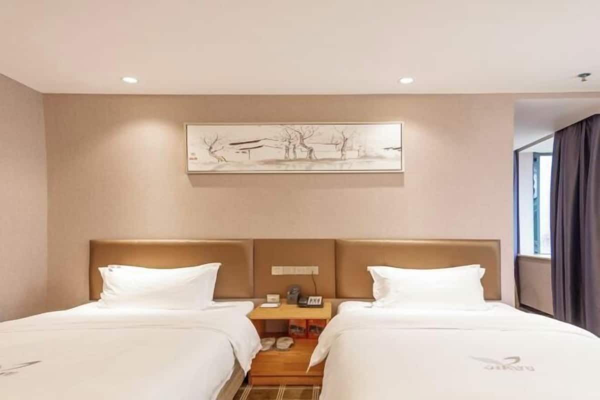A hotel room with two beds, a nightstand, a painting, and a window with curtains.