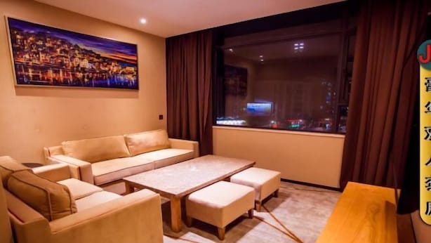 Una habitación con sofá, una mesa y vistas a la ciudad de noche.
