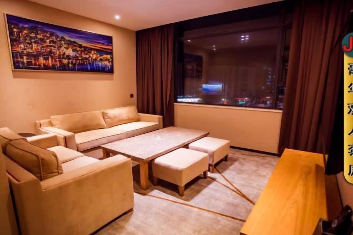A room with a sofa, a table, and a view of a cityscape at night.