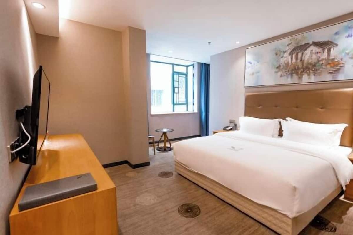 A hotel room with a bed, a television, a desk, and a window with a view.