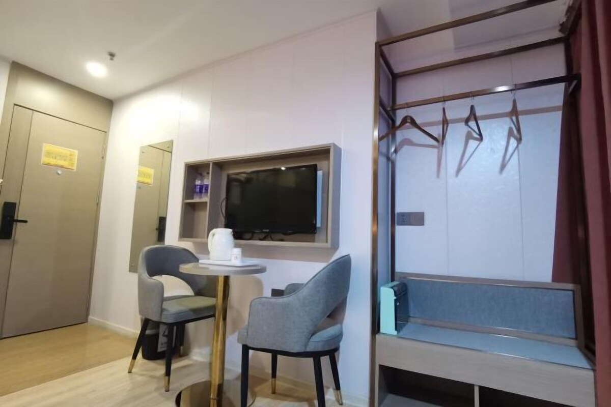 A hotel room with a seating area, a television, and a wardrobe.