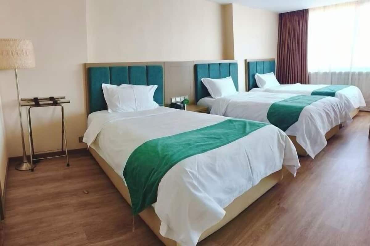 Ein Hotelzimmer mit zwei Betten, einem Nachttisch, einer Lampe und einem Fenster mit Vorhängen.