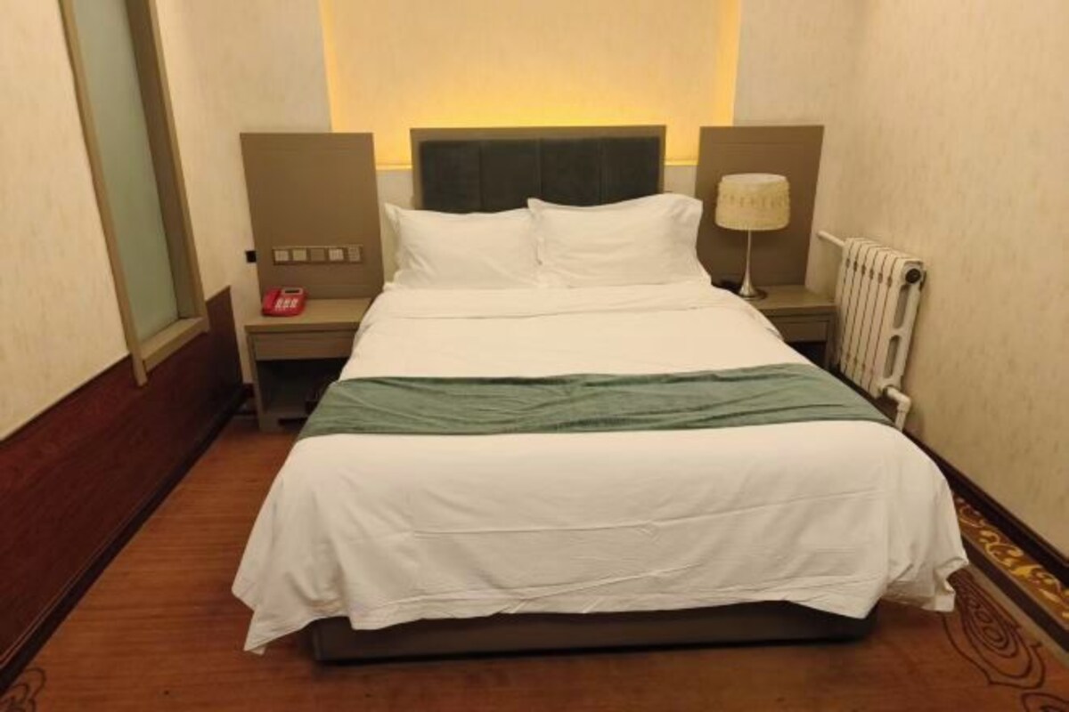 Ein Hotelzimmer mit Bett, Nachttisch, Lampe und Telefon.