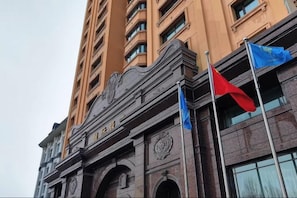 A multi-story building with a prominent entrance featuring a clock and a decorative archway. - International Hotel (Hegang)