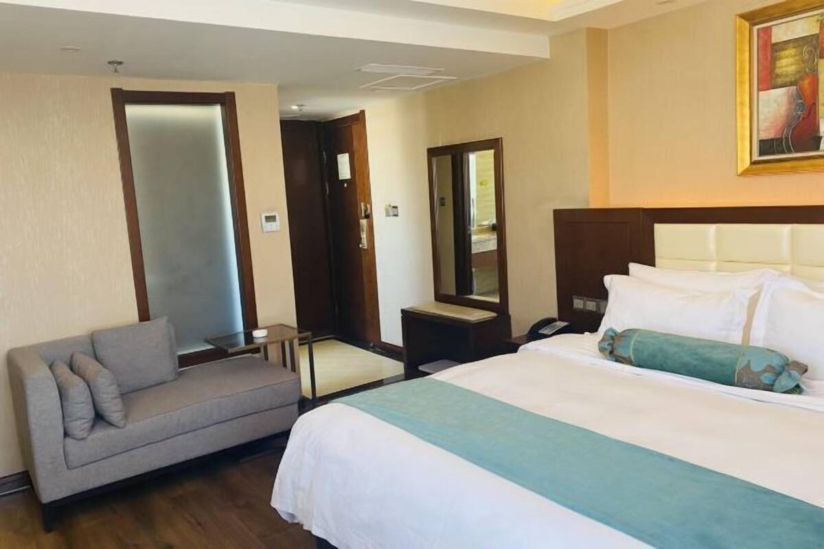 Hotellihuone, jossa on sänky, sohva, pieni pöytä ja peili.