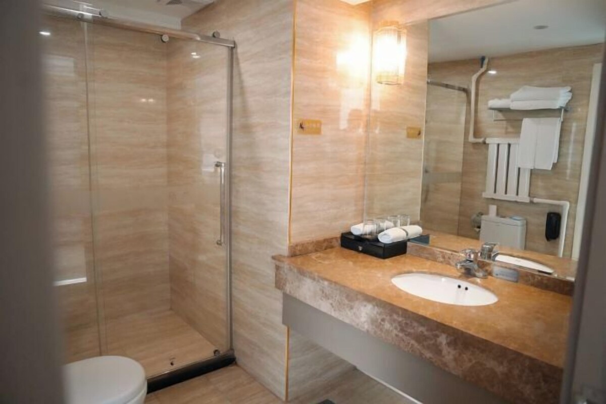 A modern bathroom with a glass-enclosed shower, a sink with a marble countertop, and a large mirror.