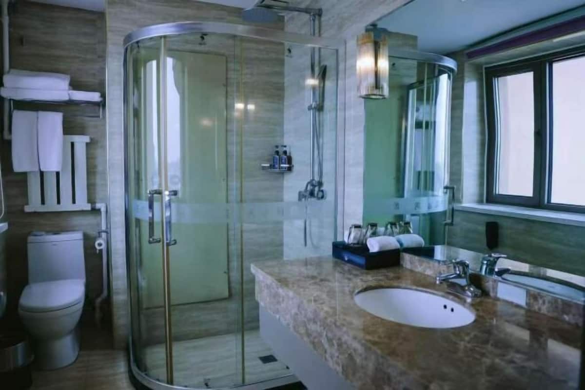 Ein modernes Badezimmer mit einer gläsernen Duschkabine, einem мрамо́рным Waschbecken und einem großen Spiegel.