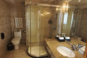 A modern bathroom with a glass-enclosed shower, a toilet, and a sink with a vanity. - Runsha International Hotel (Hegang)