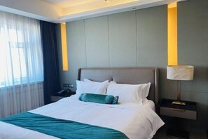 Hotellihuone, jossa on suuri sänky, yöpöytälamppu ja yöpöytä.