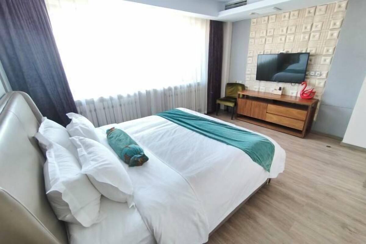 A hotel room with a bed, a TV, a desk, and a chair.