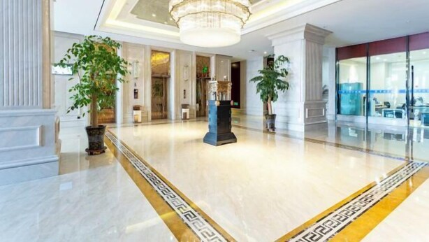 Eine geräumige Lobby mit Marmorboden, einer großen Chandelier und Zimmerpflanzen.