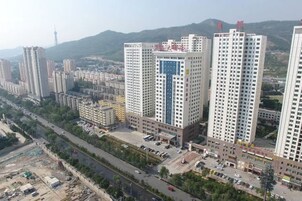 Un edificio alto con varios pisos, rodeado de otros edificios y un cielo despejado.