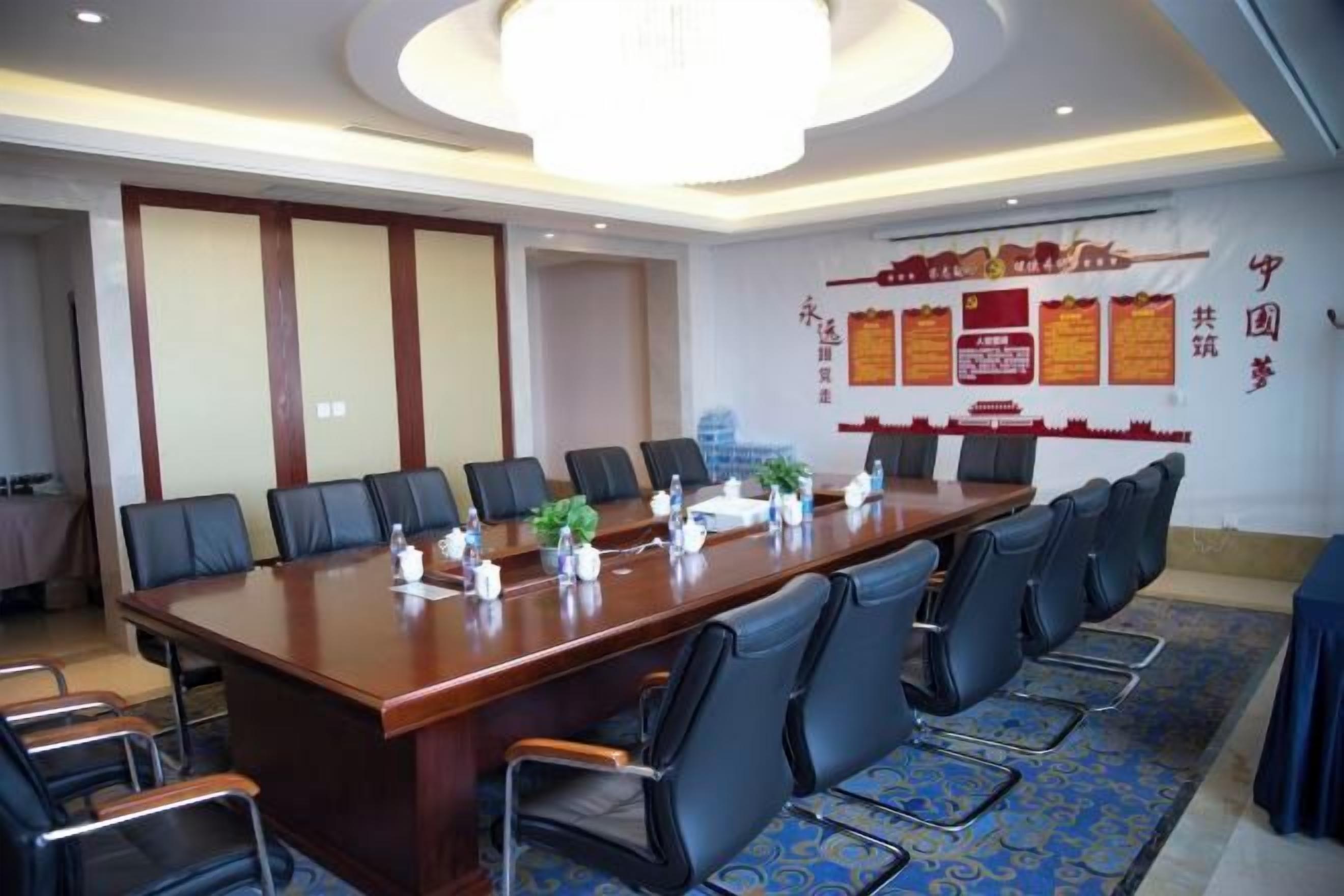 A conference room with a long table, multiple chairs, and a chandelier.