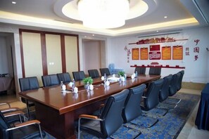 A conference room with a long table, multiple chairs, and a chandelier. - Guoluo Hotel (Xining)