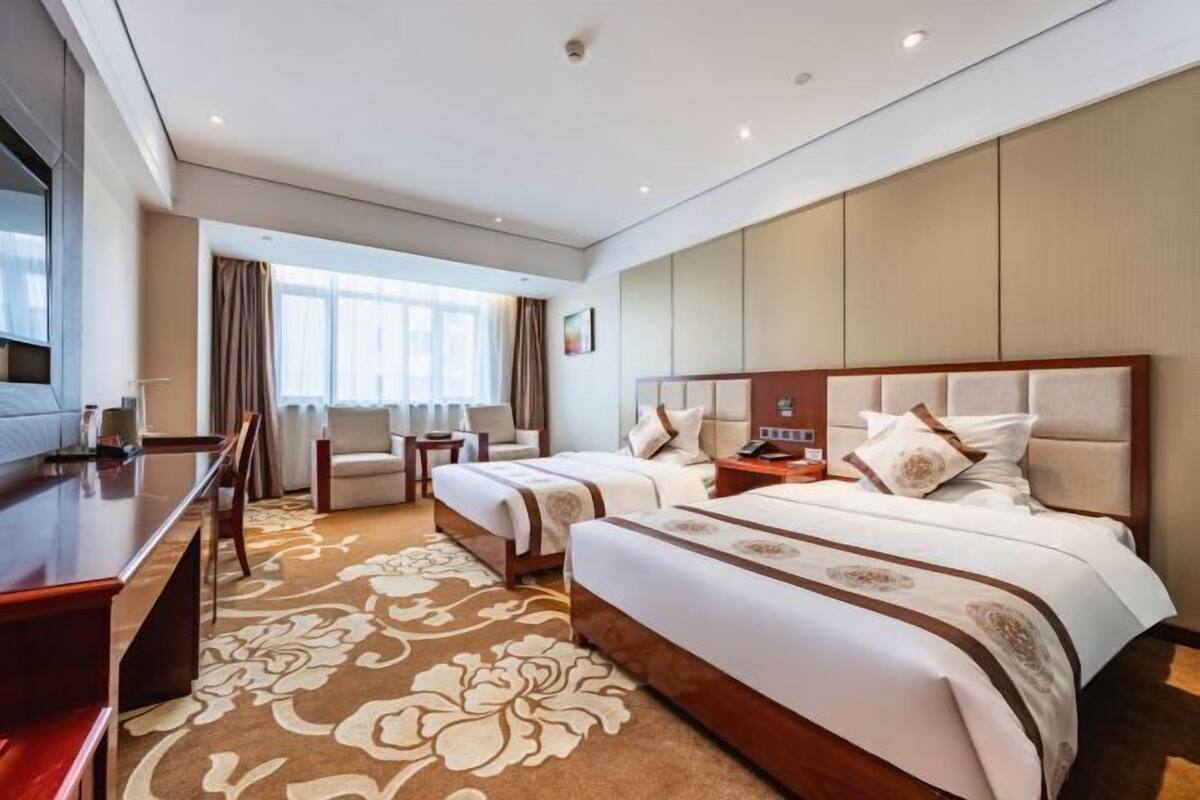Quarto de hotel com uma cama grande, uma escrivaninha, uma cadeira e uma televisão.