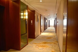A hotel corridor with wooden doors, a carpeted floor, and a long hallway. - Guoluo Hotel (Xining)