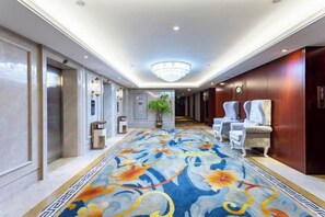 Un pasillo de hotel con alfombra estampada, un candelabro y zonas de estar.
