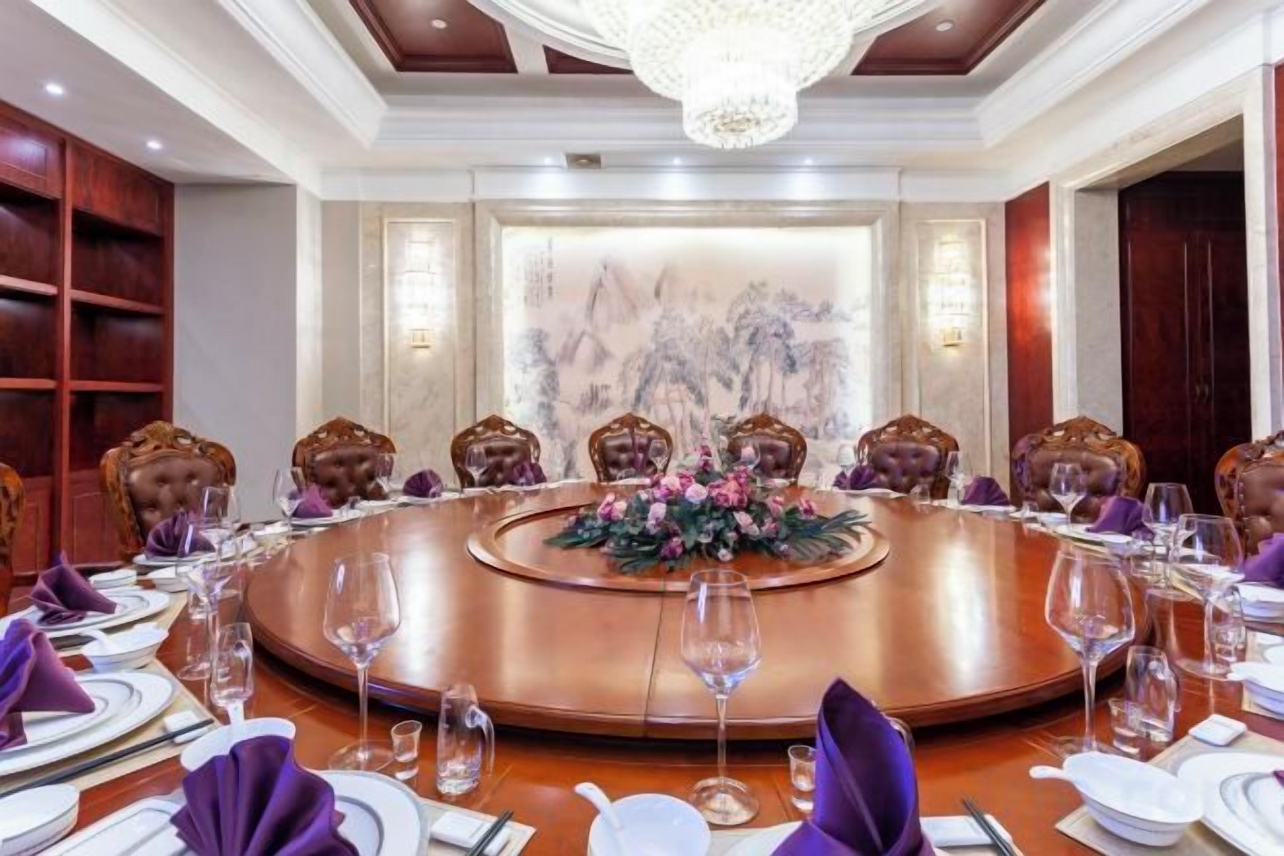 A conference room with a round table, chairs, and a floral centerpiece.