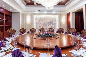 A conference room with a round table, chairs, and a floral centerpiece. - Guoluo Hotel (Xining)