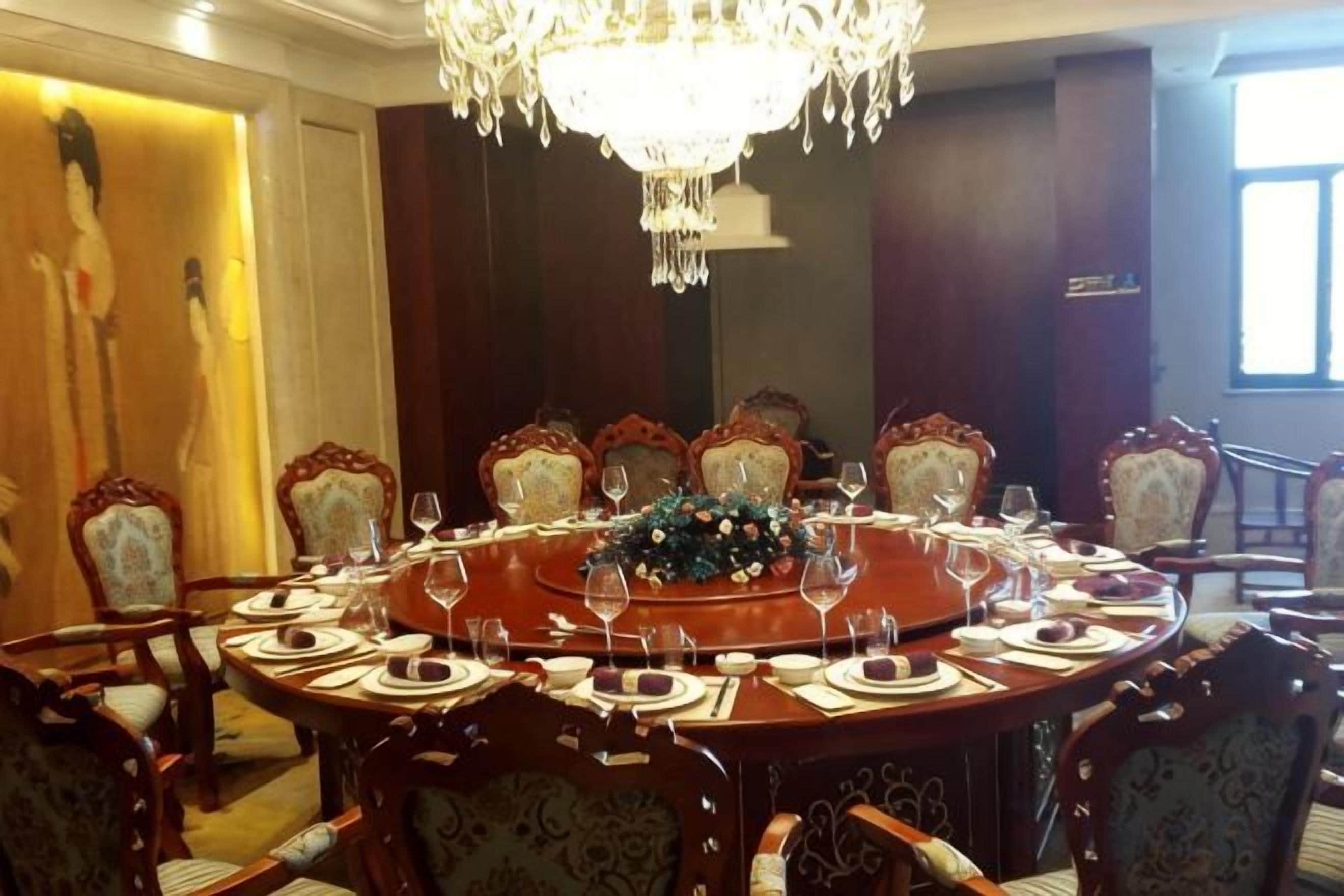 A formal dining room with a round table, ornate chairs, and a chandelier.