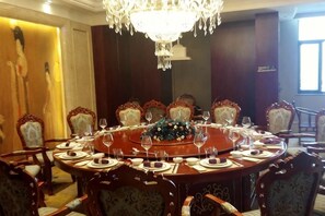 Un comedor elegante con una mesa redonda, sillas ornamentadas y un candelabro.