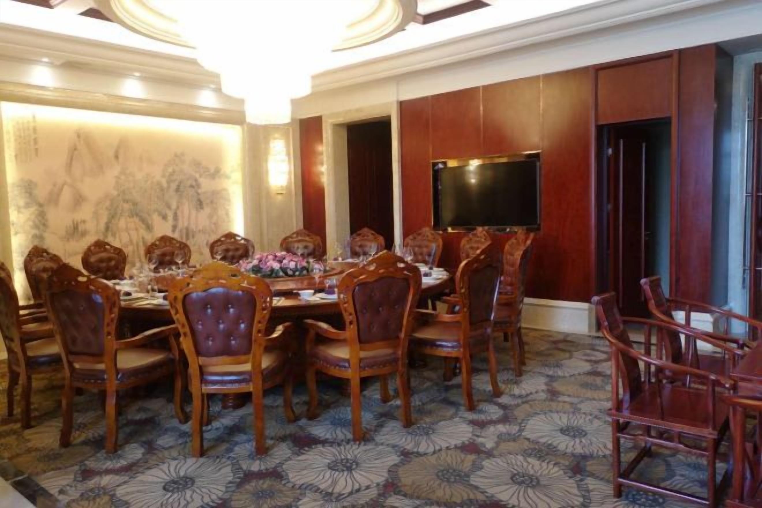 Un comedor con una mesa redonda, varias sillas y una pantalla de televisión.