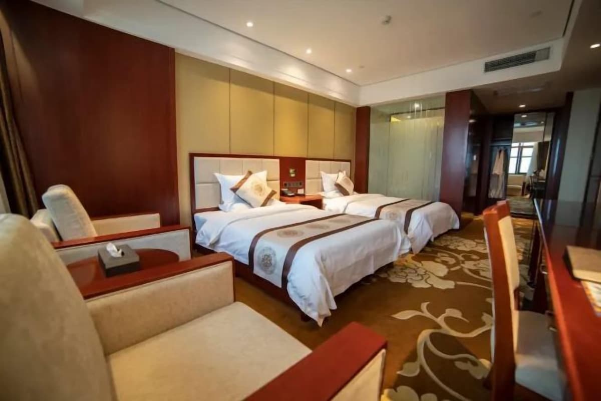 A hotel room with two beds, a sofa, a desk, and a chair.