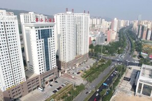 A high-rise building with multiple floors, a parking area, and a road with vehicles.
