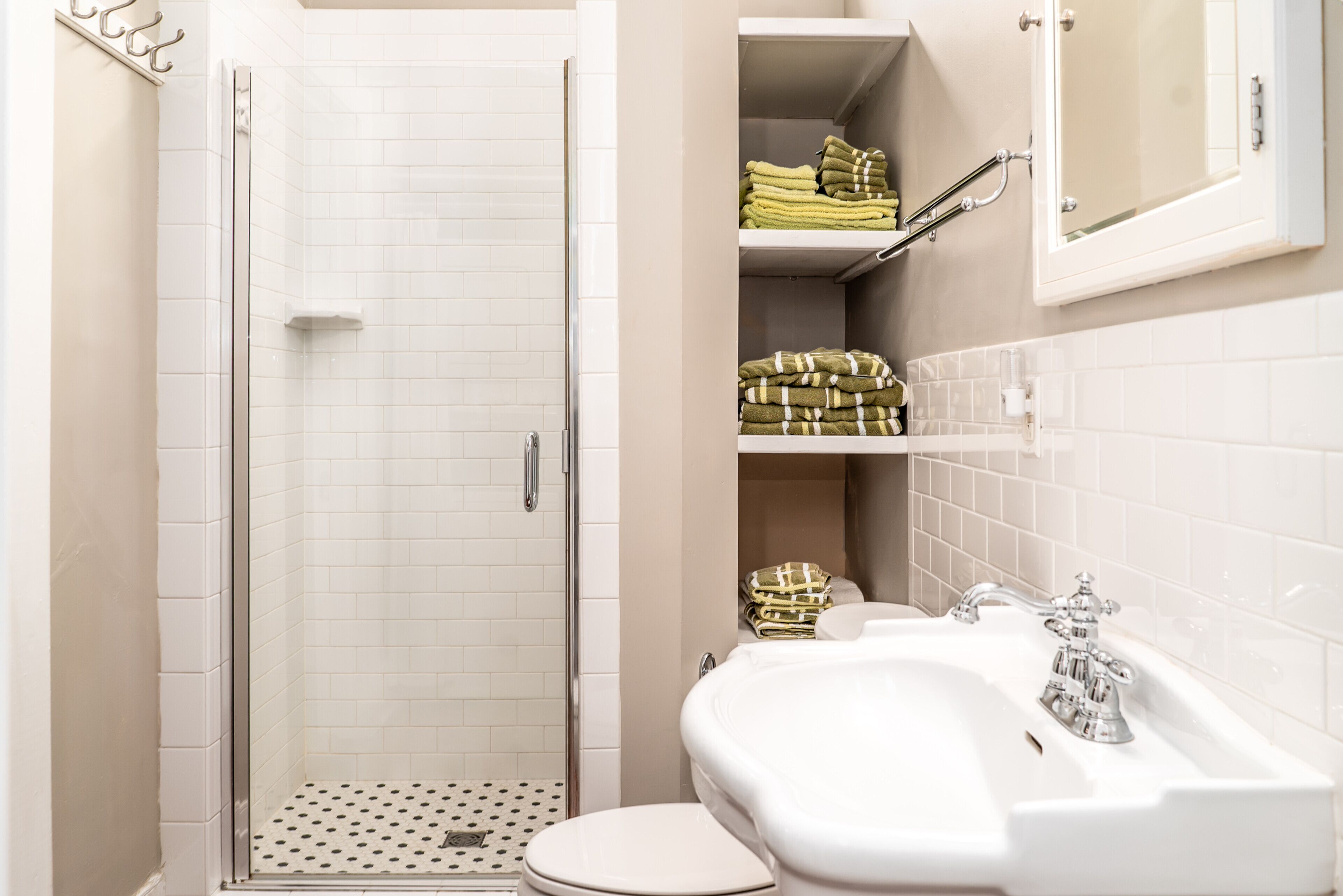 Une salle de bain équipée d’une douche, de toilettes, d’un lavabo et d’un espace pour ranger les serviettes.