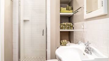 Une salle de bain équipée d’une douche, de toilettes, d’un lavabo et d’un espace pour ranger les serviettes.