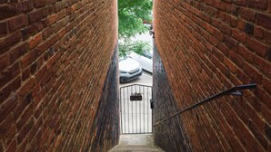 Eine schmale Ziegelsteintreppe führt zu einem verschlossenen Eingang.