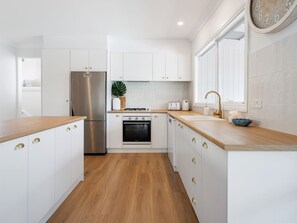 A modern kitchen with white cabinets, stainless steel appliances, and a wooden countertop. - Rye Baby by Ready Set Stay- Main & Guest House (Rye)