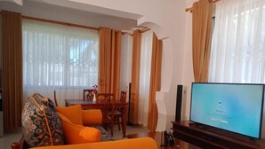 A living room with a sofa, a television, and a dining area with a table and chairs.
