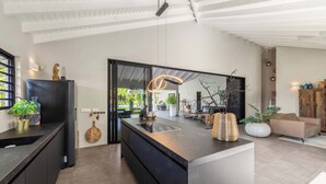 Une cuisine moderne dotée d’un grand îlot central, de meubles de rangement noirs et d’un élégant plan de travail.