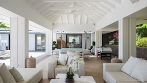 Amplio espacio interior con techo alto, comedor con mesa y sillas, y zona de estar con sofás y una mesita de centro.