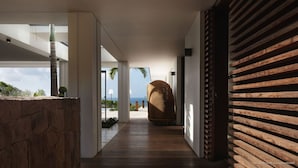 Un interior moderno con piso de madera, un sillón grande tejido y vista al océano.